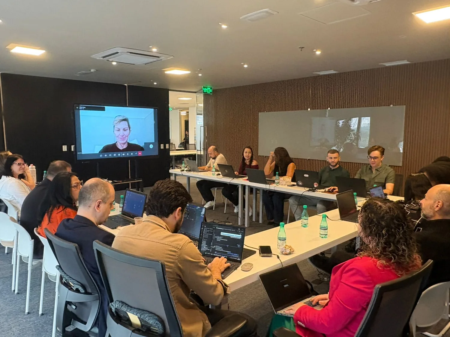 Equipe da SinergyRH reunida em torno de uma mesa com notebooks, em reunião com participante por videochamada